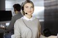 Blonde business woman talking by headset while sitting in modern call center office. Telemarketing and customer service Royalty Free Stock Photo