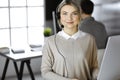 Blonde business woman talking by headset while sitting in modern call center office. Telemarketing and customer service Royalty Free Stock Photo