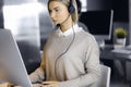 Blonde business woman talking by headset while sitting in modern call center office. Telemarketing and customer service Royalty Free Stock Photo