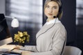 Blonde business woman talking by headset while sitting in modern call center office. Telemarketing and customer service Royalty Free Stock Photo
