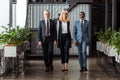 Blonde businesswoman walking with handsome multicultural partners in office Royalty Free Stock Photo