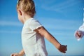 Blonde Caucasian child girl running against blue clear sky background. Happy carefree childhood. Kids. Children. Family Royalty Free Stock Photo