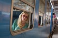 Blonde caucasian woman riding a train, looking trough window.