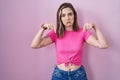 Blonde caucasian woman standing over pink background pointing down looking sad and upset, indicating direction with fingers, Royalty Free Stock Photo