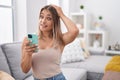 Blonde caucasian woman using smartphone typing message sitting on the sofa stressed and frustrated with hand on head, surprised Royalty Free Stock Photo