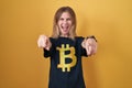 Blonde caucasian woman wearing bitcoin t shirt pointing to you and the camera with fingers, smiling positive and cheerful Royalty Free Stock Photo