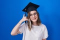 Blonde caucasian woman wearing graduation cap smiling doing phone gesture with hand and fingers like talking on the telephone Royalty Free Stock Photo
