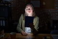 Blonde caucasian woman working at the office at night looking at the camera blowing a kiss on air being lovely and sexy Royalty Free Stock Photo