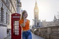A blonde city woman walks in front of a red telephone booth and Big Ben tower in London Royalty Free Stock Photo