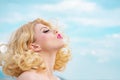 Blonde with curly hairstyle and red lips. Long hair on sky background with copy space. Woman Head close up. Royalty Free Stock Photo