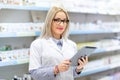 Blonde doctor in white uniform using tablet and technology in pharmaceutical or medical field Royalty Free Stock Photo