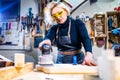 blonde female carpenter using tools for her work in a woodshop Royalty Free Stock Photo