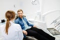 Blonde female dentist in dental office talking with male patient and preparing for treatment Royalty Free Stock Photo