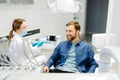 Blonde female dentist in dental office talking with male patient and preparing for treatment. Handsome bearded man in dentist Royalty Free Stock Photo