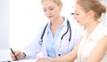 Blonde female doctor and patient talking in hospital office. Health care and client service in medicine Royalty Free Stock Photo