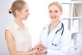 Blonde female doctor and patient talking in hospital office. Health care and client service in medicine Royalty Free Stock Photo