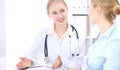 Blonde female doctor and patient talking in hospital office. Health care and client service in medicine Royalty Free Stock Photo