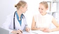 Blonde female doctor and patient talking in hospital office. Health care and client service in medicine Royalty Free Stock Photo