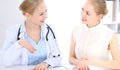 Blonde female doctor and patient talking in hospital office. Health care and client service in medicine Royalty Free Stock Photo