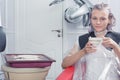 A blonde female dying hair in hairdressing salon