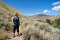 Blonde female hiker 30s looks off into the distance while on a mountain hike. Taken in the Salmon-Challis National Forest of