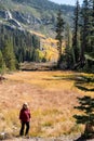 Blonde female middle aged hiker poses at Sotcher Lake in the autumn with fall colors on the tree leaves. Located near Mammoth