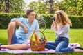 Blonde female photo shooting her boyfriend at picnic time. Royalty Free Stock Photo