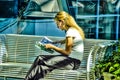 A Blonde female sitting reading a magazine