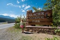 Blonde female stands and poses next to the Glacier National Park Sign in Montana USA