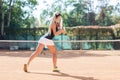 Blonde female tennis player in action. View from back.