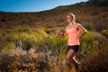 Blonde female trail runner running through a mountain landscape Royalty Free Stock Photo