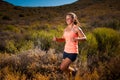 Blonde female trail runner running through a mountain landscape Royalty Free Stock Photo