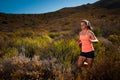 Blonde female trail runner running through a mountain landscape Royalty Free Stock Photo