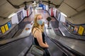 Blonde female wearing a PPE face mask traveling on an escalator at a London Underground Tube Station