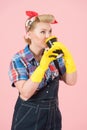 Blonde girls with yellow gloves holds and drinks from cup with yellow cover. Happy Pin-up styled woman drinks coffee.