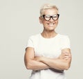 blonde fifty year old European female with stylish pixie haircut and eyeglasses smiling at camera