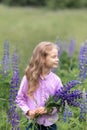 Blonde with flowers in the field.The baby is holding a bouquet of lupines