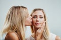 Blonde friends, one kissing another's cheek affectionately
