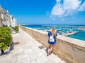 Blonde girl admires the harbour of Otranto, Apulia, Italy.