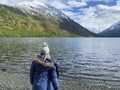 Blonde girl from the back is standing on beach,lake with water.Person without a face,beautiful snow-capped mountains Royalty Free Stock Photo