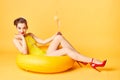 Blonde girl in a bathing suit and with a cocktail in her hands sits on an inflatable circle Royalty Free Stock Photo