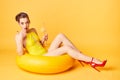 Blonde girl in a bathing suit and with a cocktail in her hands sits on an inflatable circle Royalty Free Stock Photo