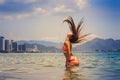 Blonde girl in bikini stands in sea shaken head lifts hair up