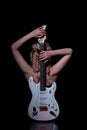 A blonde girl on a black background is sitting with her back and a white guitar Royalty Free Stock Photo