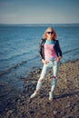 Beautiful blonde in ripped jeans posing on the shore of the blue sea Royalty Free Stock Photo