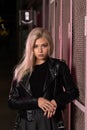 blonde girl in a black leather jacket posing on a dark background and pink lattice, rock style Royalty Free Stock Photo