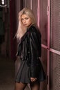 blonde girl in a black leather jacket posing on a dark background and pink lattice, rock style Royalty Free Stock Photo