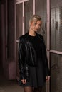 blonde girl in a black leather jacket posing on a dark background and pink lattice, rock style Royalty Free Stock Photo