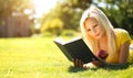 Blonde Girl with Book and Apple on Green Grass. Beautiful Woman