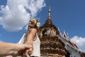 Blonde girl with a braid and a flower in her ear holding hands in front of a Buddhist temple